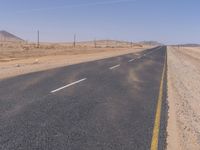 empty road near desert area with mountains in background, no people yet on it, in the distance are bushes and sparse clouds