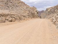 a small vehicle traveling across a barren road between some large rocks and boulders on one side