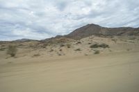 a view out of a car window showing desert areas with sand and mountains in the distance