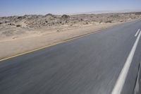 the view from a speeding motorcycle on an empty desert highway with a person riding an automobile