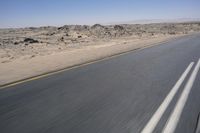 the view from a speeding motorcycle on an empty desert highway with a person riding an automobile