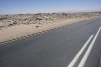 the view from a speeding motorcycle on an empty desert highway with a person riding an automobile