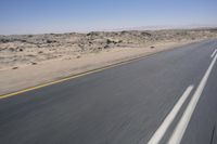 the view from a speeding motorcycle on an empty desert highway with a person riding an automobile