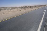 the view from a speeding motorcycle on an empty desert highway with a person riding an automobile