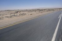 the view from a speeding motorcycle on an empty desert highway with a person riding an automobile