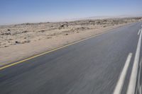 the view from a speeding motorcycle on an empty desert highway with a person riding an automobile