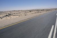 the view from a speeding motorcycle on an empty desert highway with a person riding an automobile