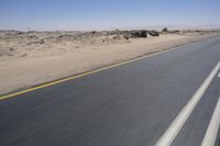 the view from a speeding motorcycle on an empty desert highway with a person riding an automobile