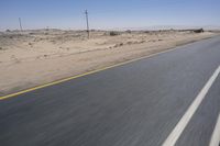 the view from a speeding motorcycle on an empty desert highway with a person riding an automobile