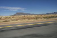 a picture of a wide open highway and a mountain in the distance that is in the desert