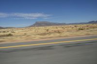 a picture of a wide open highway and a mountain in the distance that is in the desert