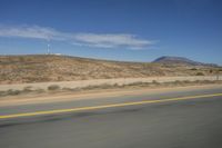 a picture of a wide open highway and a mountain in the distance that is in the desert