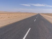 empty road near desert area with mountains in background, no people yet on it, in the distance are bushes and sparse clouds