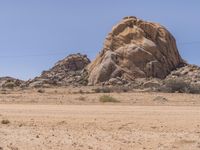 there is a large rock sitting in the desert with no one around it and no one standing at it