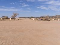 a building is sitting in the desert outside a fenced off area with benches and a gate