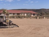 an old car is parked in the desert area with buildings in the background and palm trees growing in the mud