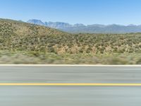 view of the mountains from a moving car window and a highway as it drives near the desert