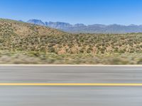 view of the mountains from a moving car window and a highway as it drives near the desert