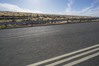 a motorcycle that is sitting on a highway in the middle of nowhere with the sun behind