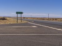 the empty road runs into an empty field, with sign pointing to different directions for a highway