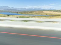 a motorcycle rider wearing black leathers rides down the highway in front of a lake