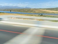 a motorcycle rider wearing black leathers rides down the highway in front of a lake