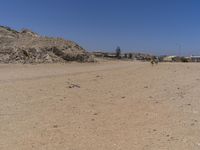 there are some people standing in the dirt near a mountain area in a desert landscape