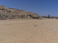 there are some people standing in the dirt near a mountain area in a desert landscape