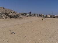 there are some people standing in the dirt near a mountain area in a desert landscape