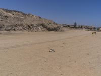 there are some people standing in the dirt near a mountain area in a desert landscape