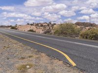 the empty street is on the rocky hill side and yellow paint shows the line of a curving road