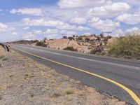 the empty street is on the rocky hill side and yellow paint shows the line of a curving road