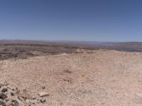 a large desert area with a few rocks on the ground and mountains in the distance