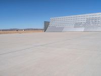 an airplane sitting in an airport next to the runway with no clouds or rain on it