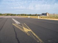 the airplane is traveling on an empty runway while it's in the air that appears to be painted with yellow chalk