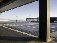 an empty parking lot is seen through the window of an airplane hangar where a plane is parked