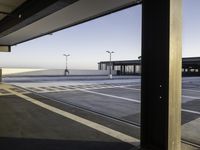 an empty parking lot is seen through the window of an airplane hangar where a plane is parked