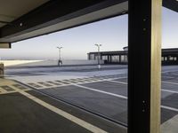 an empty parking lot is seen through the window of an airplane hangar where a plane is parked