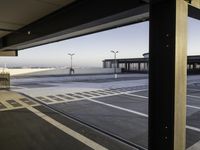 an empty parking lot is seen through the window of an airplane hangar where a plane is parked