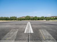 airplane line on a paved airport runway on a clear day with trees in the background