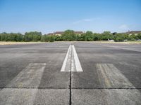 airplane line on a paved airport runway on a clear day with trees in the background