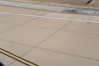 the airplane is getting ready for take off on the runway at an airport with brown grass and blue sky