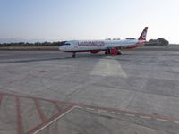 there is a red and white plane on the runway at the airport's gate