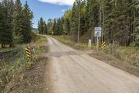 a dirt road surrounded by trees with caution signs on the side of the road next to it