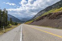 the road is lined with mountains and pines, with the road passing by it is very windy