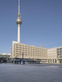 the television tower stands tall behind other buildings, in the city square of a large city