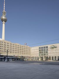 the television tower stands tall behind other buildings, in the city square of a large city