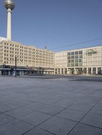 the television tower stands tall behind other buildings, in the city square of a large city