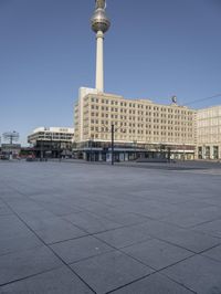 the television tower stands tall behind other buildings, in the city square of a large city