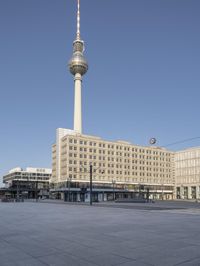 the television tower stands tall behind other buildings, in the city square of a large city